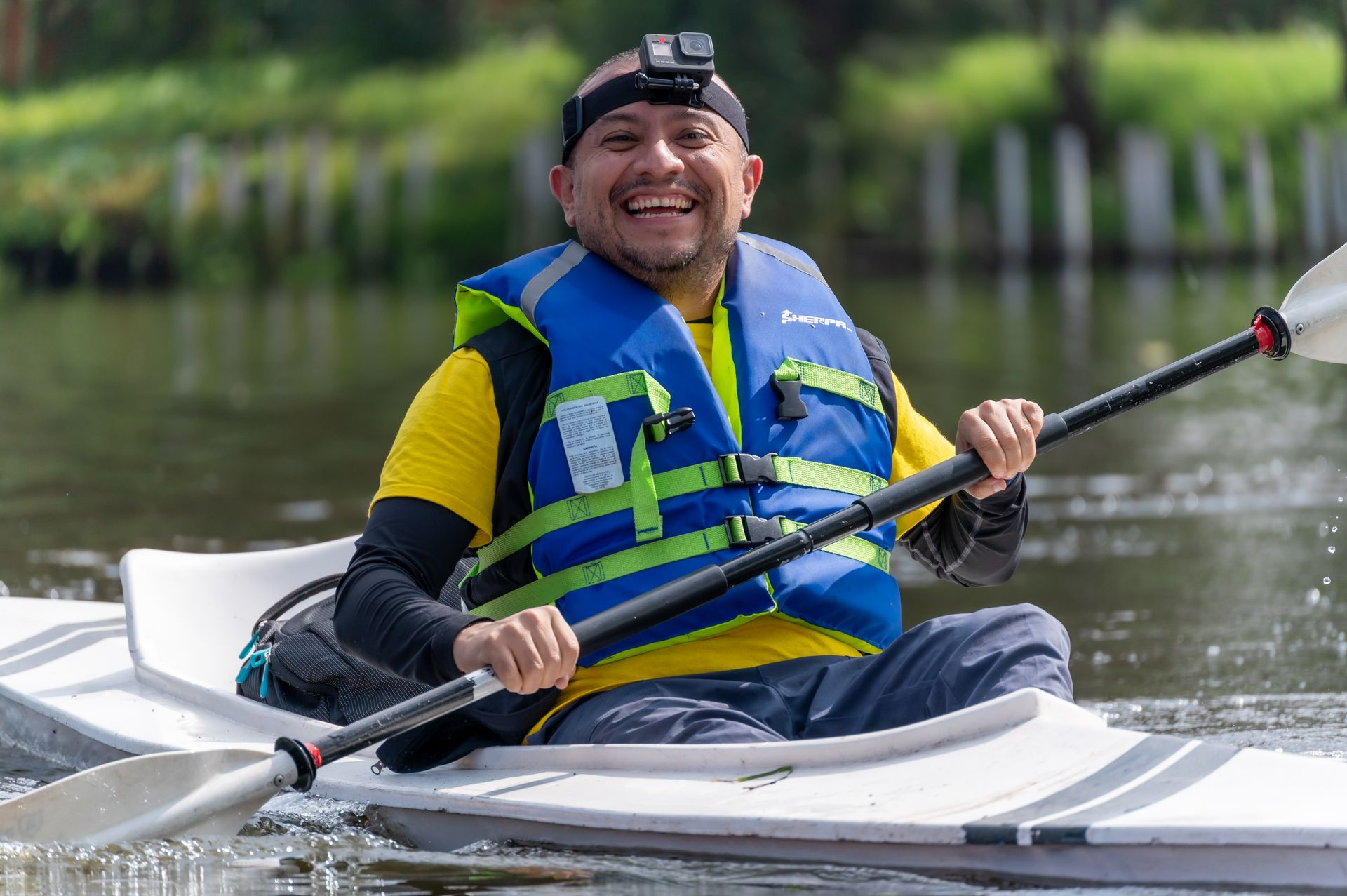 Smiling paddler in a life jacket kayaking on the water