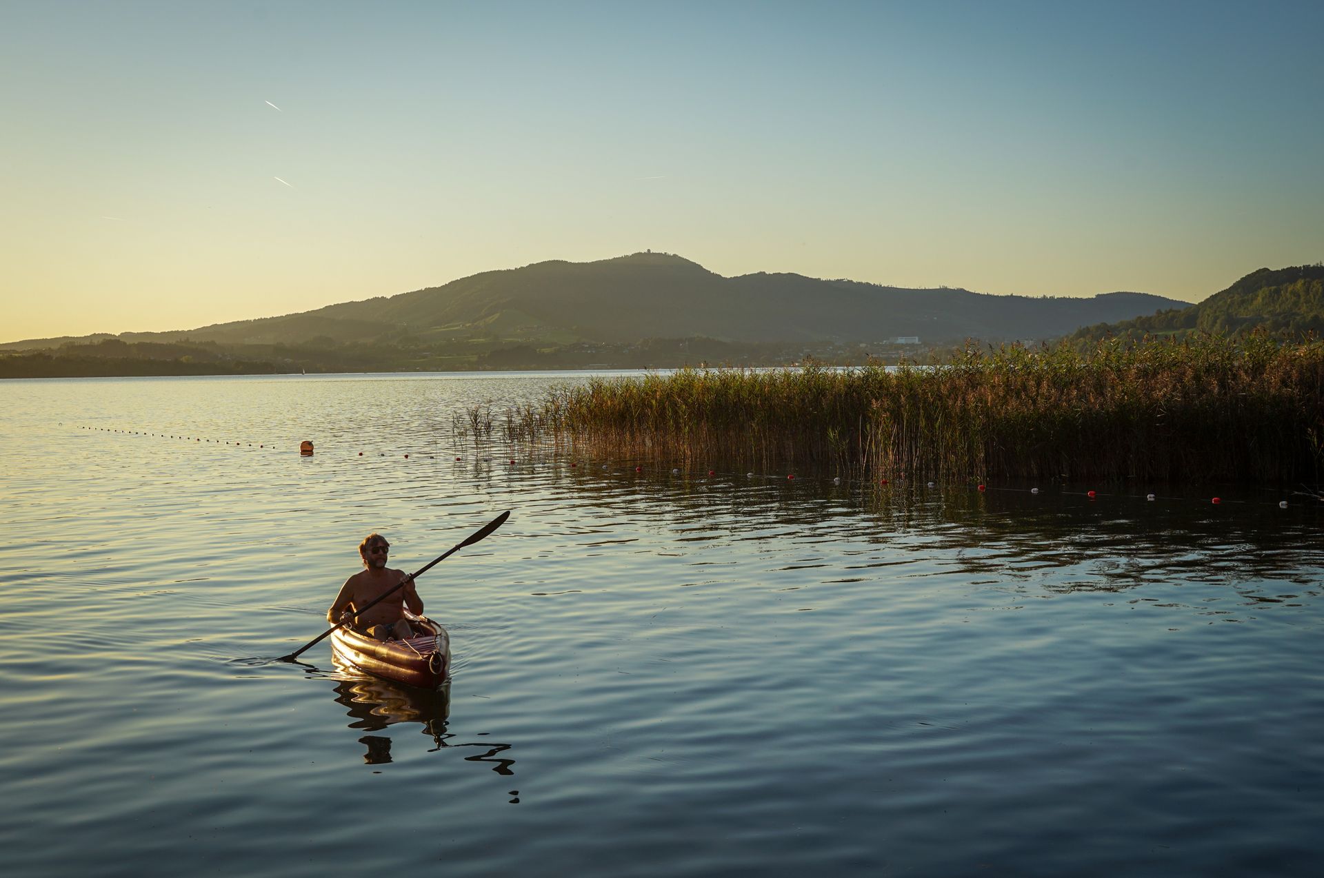 Kayaker on a sunny lake at golden hour